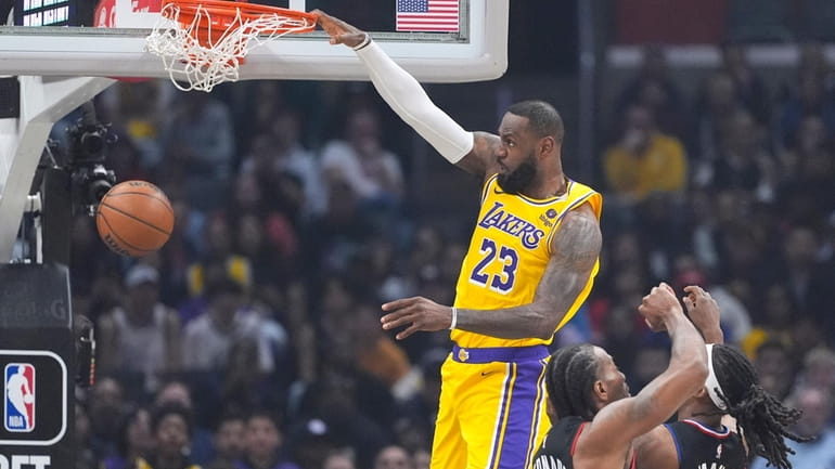 Los Angeles Lakers forward LeBron James, left, dunks as Los...