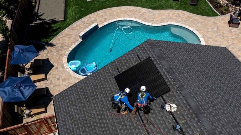 Workers install SunPower solar panels on a home in Napa, California,...