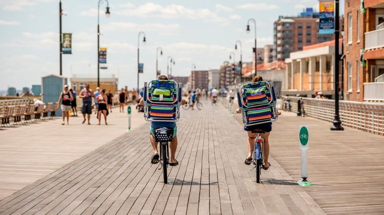 Beachgoers bike along the Long Beach boardwalk.