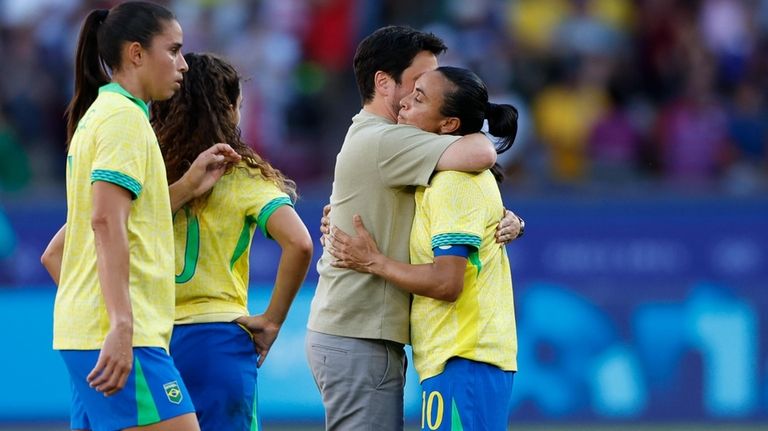 Brazil's Marta, right, is embraced by Brazil's head coach Elias...