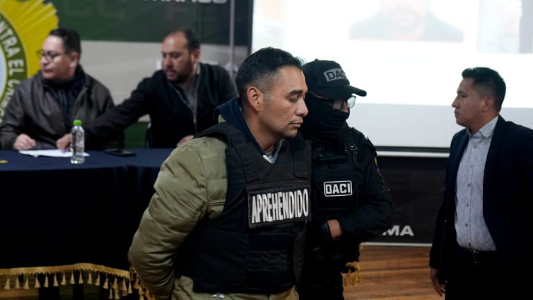 Miguel Angel Burgos is presented to the press in handcuffs...