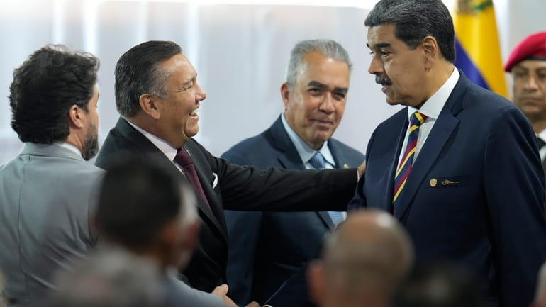 Venezuelan President Nicolas Maduro, right, shakes hands with presidential candidate...