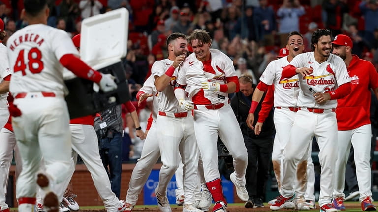 St. Louis Cardinals' Nolan Gorman, center right, is mobbed by...