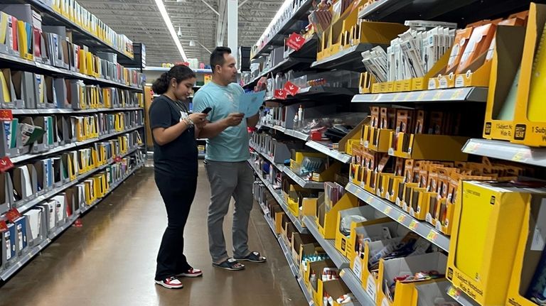 Jose Hernandez, 32, of Copiague, consults a school supply list...