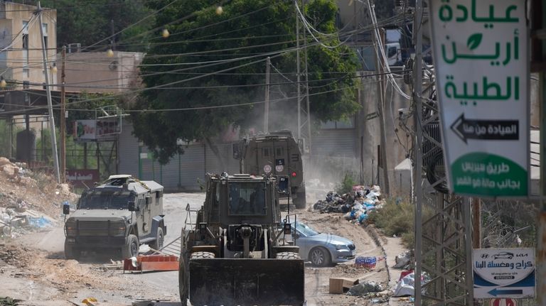 A bulldozer from the Israeli forces moves on a street...