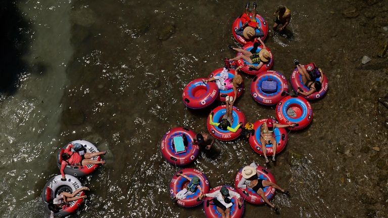 Tubers float the cool Comal River in New Braunfels, Texas,...