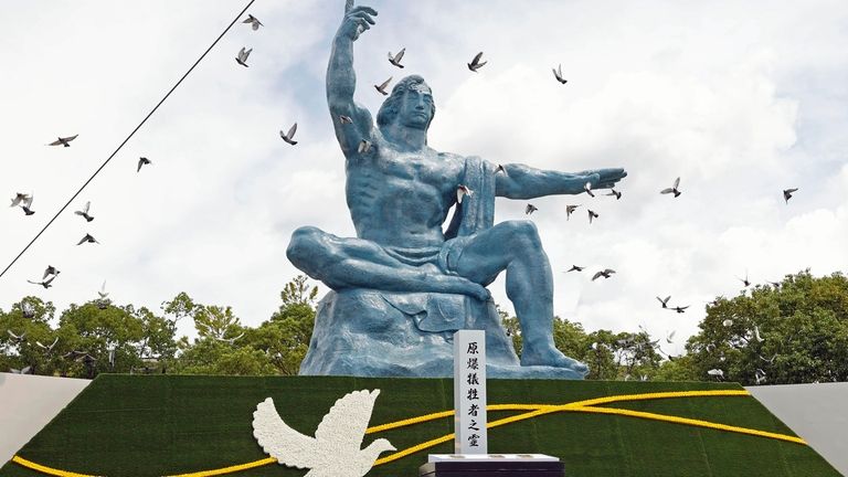 Doves fly over the Peace Statue during a ceremony to...