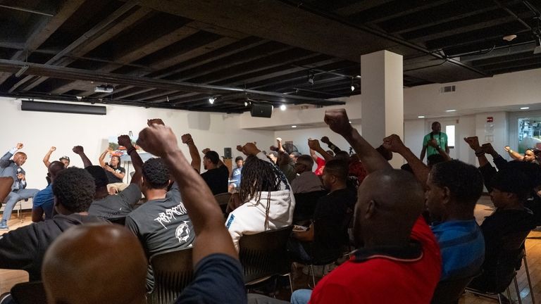 Panelists and attendees raise their fists during a Black Man...