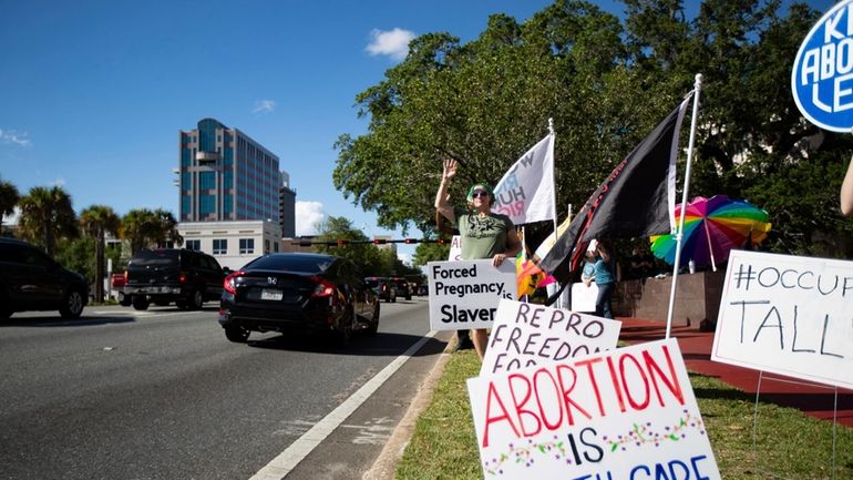 A small crowd holding signs and waving as cars pass...