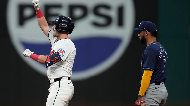 Cleveland Guardians' Lane Thomas, left, gestures from second base in...