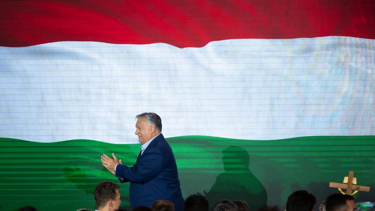 Hungarian Prime Minister Viktor Orban claps after addressing the media...
