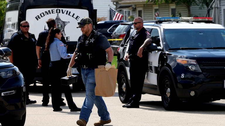 A Romeoville Police officer carries out a brown bagged marked...