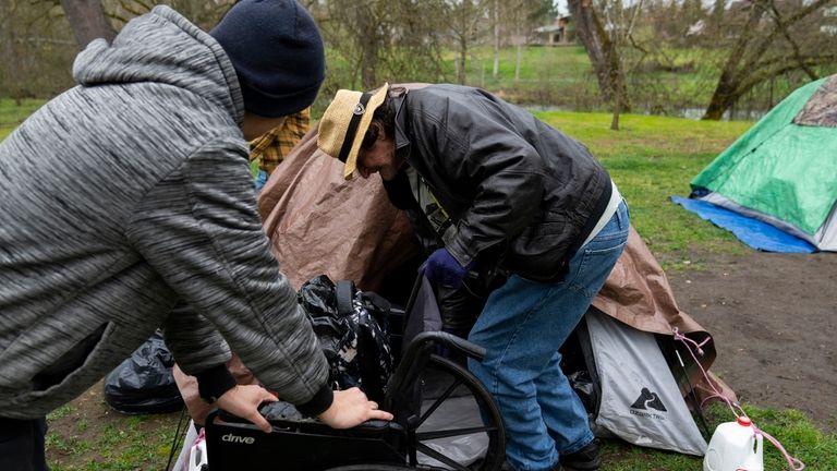 A volunteer holds on to a wheelchair as they help...