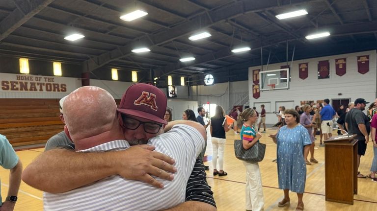 Jamie Tellier, father of Caden Tellier, hugs a student after...