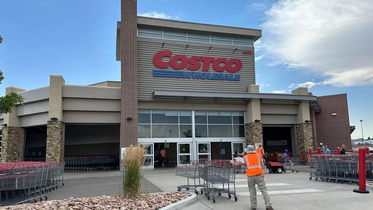 A cart wrangler works in front of a Costco warehouse...