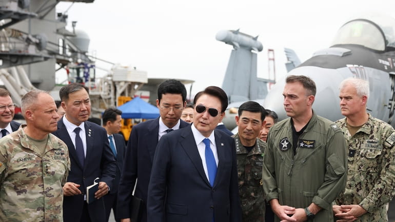 South Korean President Yoon Suk Yeol, center, boards the USS...