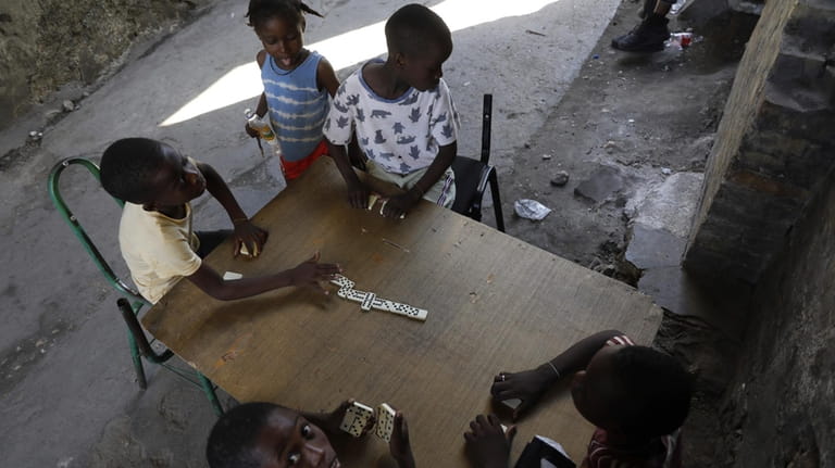 Children play dominos at a shelter for families forced to...