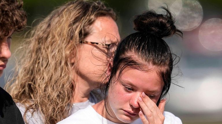 A student weeps at a makeshift memorial after a shooting...