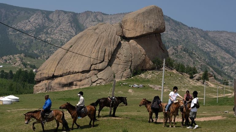 Tourists enjoy horseback riding near the iconic Turtle Rock outcrop...