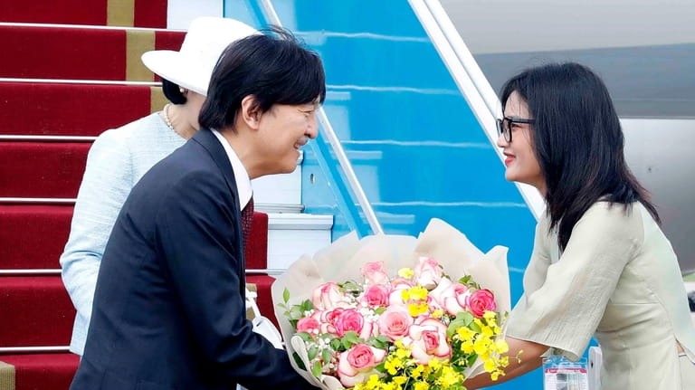 Japanese Crown Prince Akishino receives flowers from a Vietnamese official...
