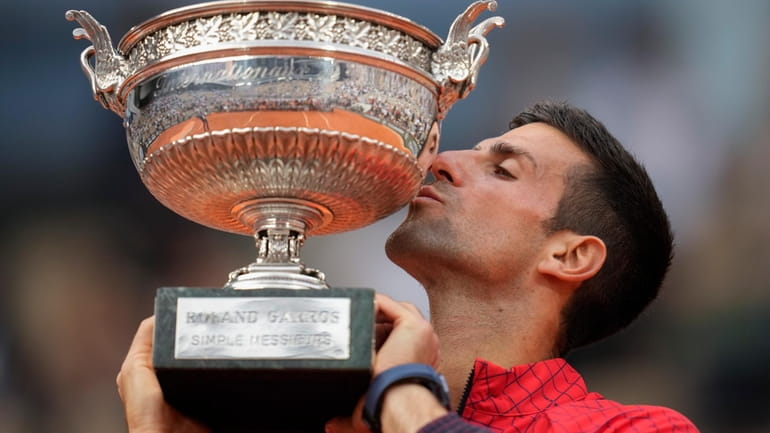 Serbia's Novak Djokovic kisses the trophy as he celebrates winning...