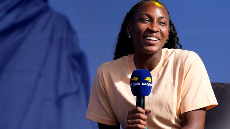 Coco Gauff smiles while speaking to the crowd at the...