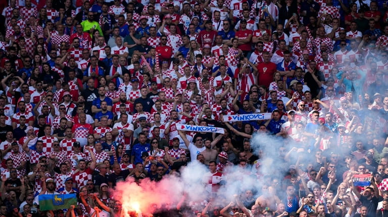 Croatian supporters light a flare as they cheer during a...