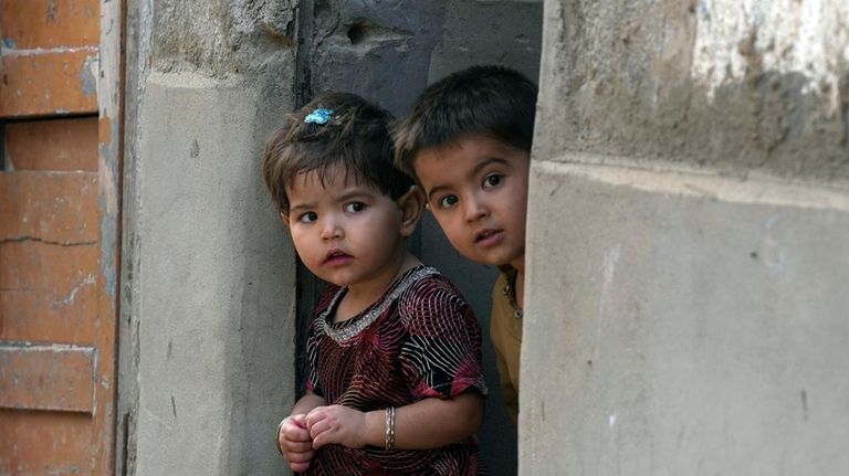 Afghan refugee children look to Pakistani police officers conducts biometric...