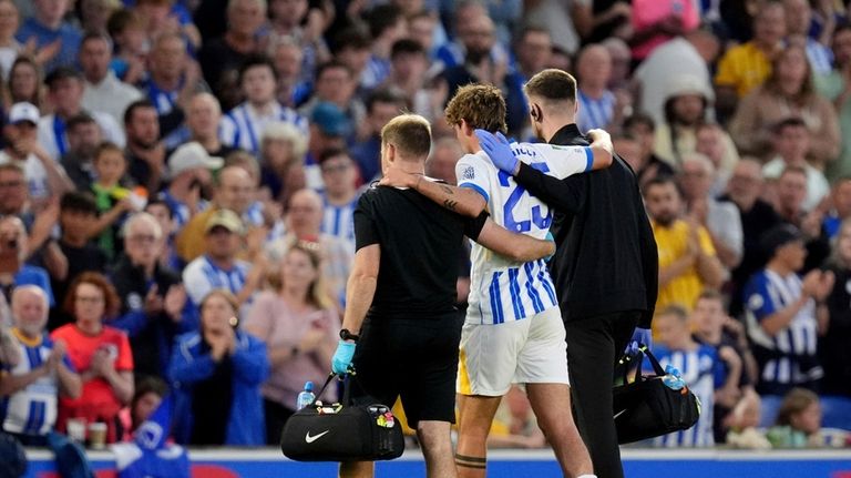 Brighton & Hove Albion's Matt O'Riley is helped from the...