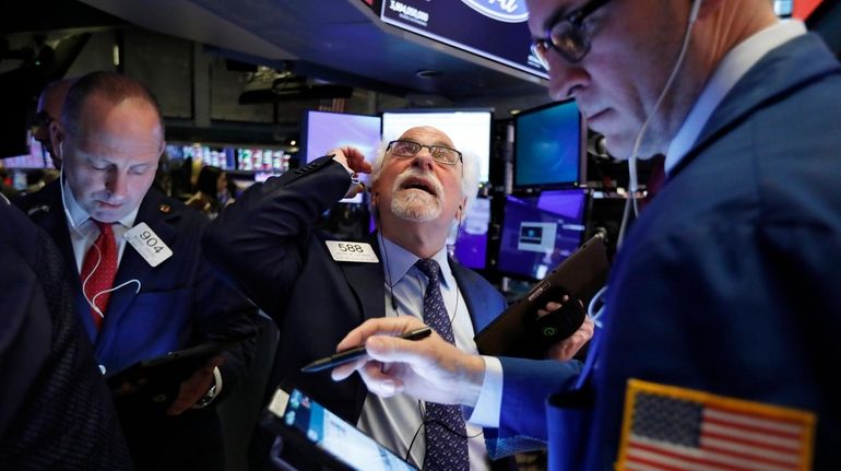 Traders Michael Urkonis, left, and Peter Tuchman, center, work on...