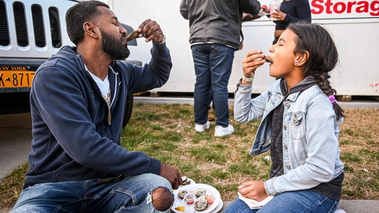 Andy and Nylah, 10, Moonassar, of Valley Stream, eat oysters...