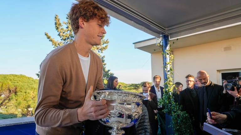 Italian tennis player Jannik Sinner carries the Australian Open trophy...