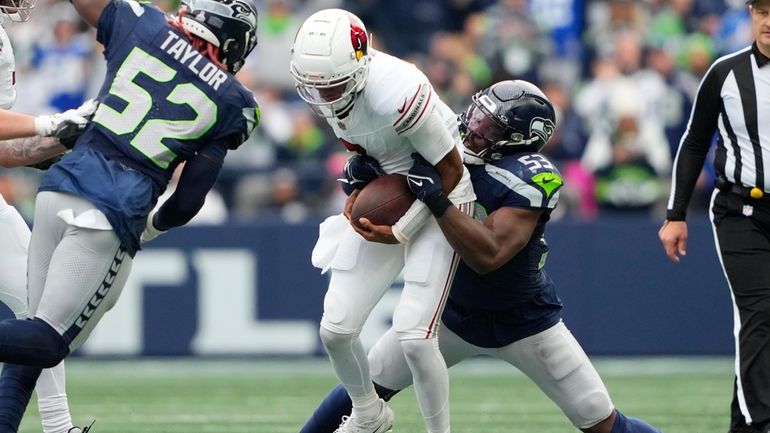 Arizona Cardinals quarterback Joshua Dobbs, center, gets taken down by...