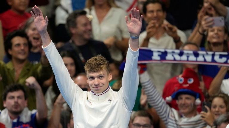 Leon Marchand of France, waves as he stands on the...