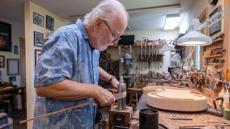 Monteleone bending wood for a guitar in his workshop.