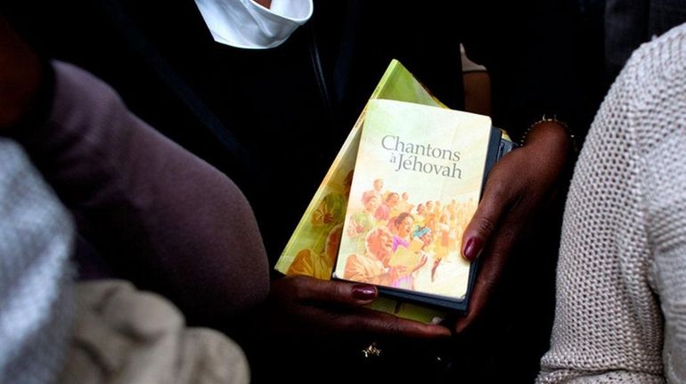 A woman holds books of prayer as she attends a...