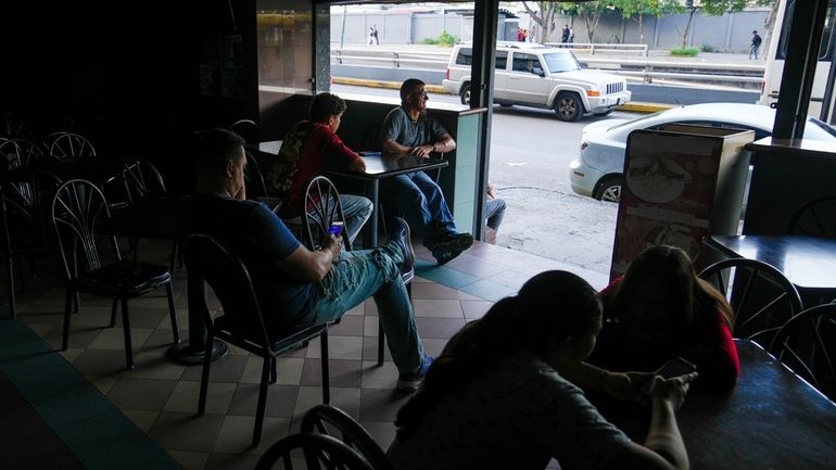 Costumers sit at a cafe during a blackout in Caracas,...