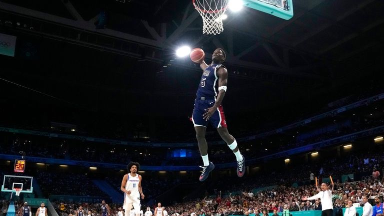 United States' Anthony Edwards, center, goes up for a dunk...