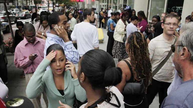 Office workers gather on a sidewalk after their building was...