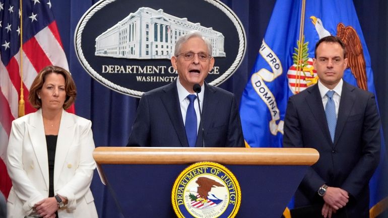 Attorney General Merrick Garland, center, speaks with reporters about an...