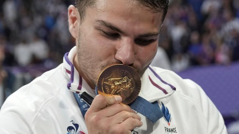 Antoine Dupont of France bites his gold medal as he...