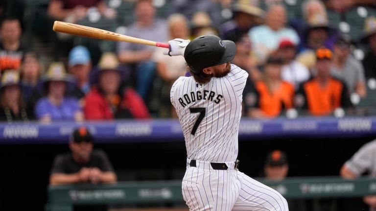 Colorado Rockies' Brendan Rodgers follows the flight of his two-run...