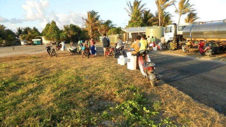 People line up at a fresh-water station on the endangered...