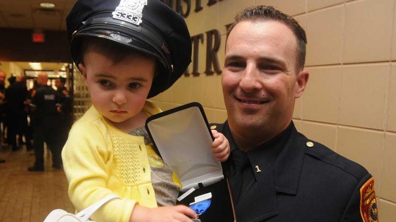 First precinct police officer John Brady holds his daughter Olivia,...