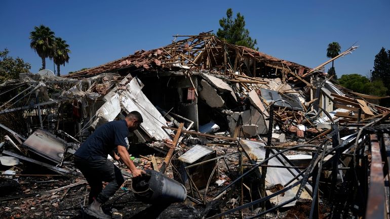 A man works next to a destroyed home after rockets...