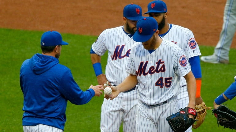 Zack Wheeler of the Mets hands the ball to manager...