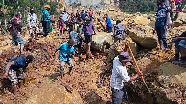 Villagers search through a landslide in Pogera village, in the...