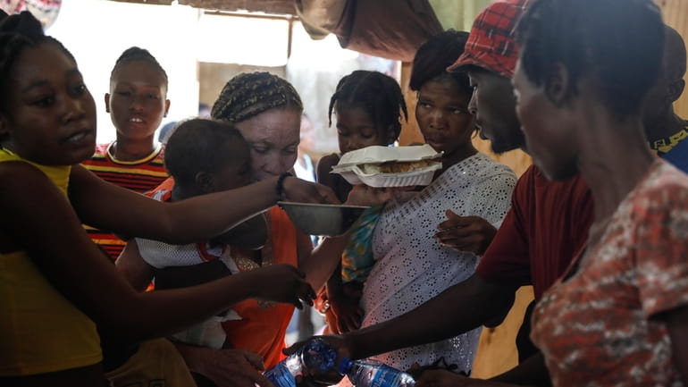 Women scuffle for plates of food for their children at...