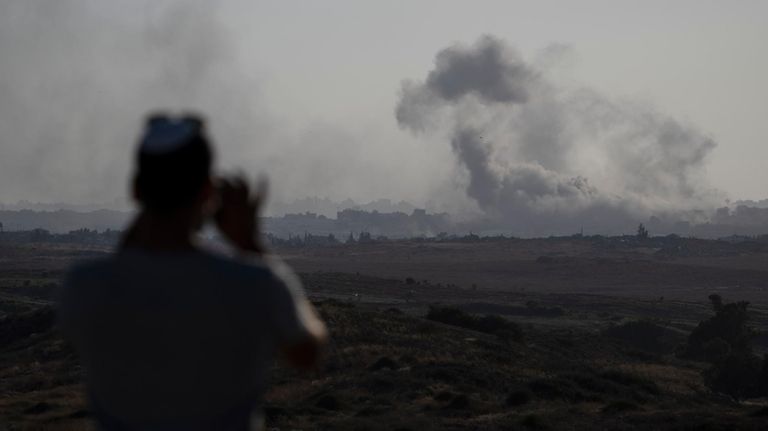 A man watches smoke rising to the sky after an...