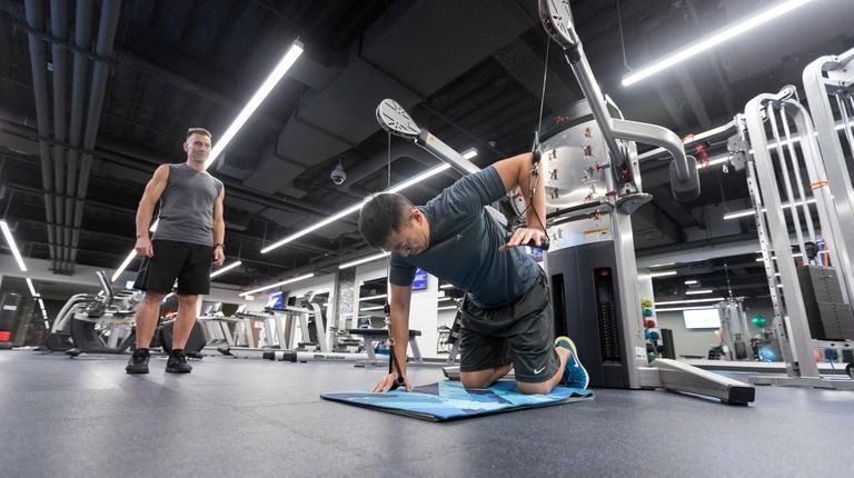 Engineer Kevin Hsu, right, works with trainer and gym manager...